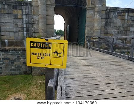 cement building with yellow caution watc your step sign