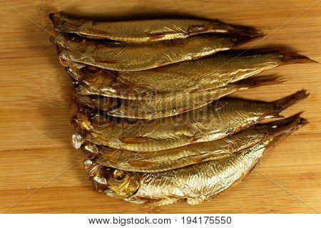 Smoked European sprats Sprattus sprattus on a wooden background.