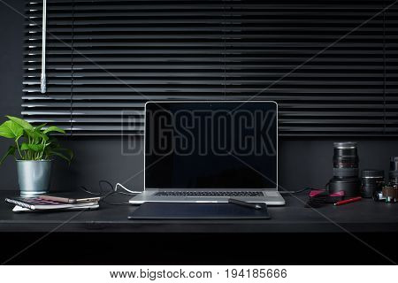 Work space on black table of a photographer or designer with laptop retro camera Stylish home studio concept of hipster . Seleted focus.