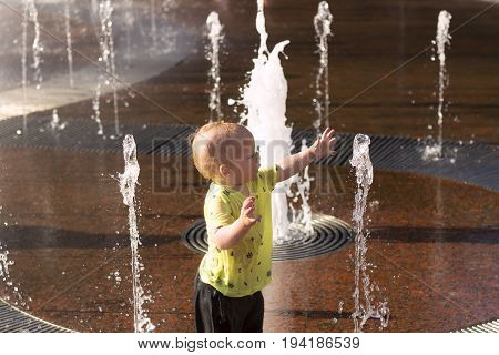 Funny Baby Boy Playing With Water Streams In Fountain