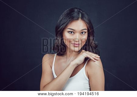 Portrait of a beautiful asian woman with makeup and light curls on black background.