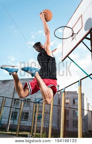 Back View Of Basketball Player Throwing Ball Into Basket During Game