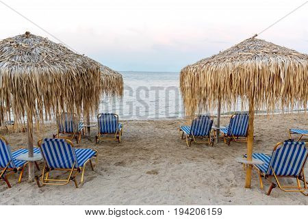 Corfu island beachside with chairs and umbrellas. Greece, sunset view