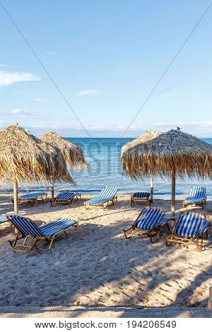 Corfu island beachside with chairs and umbrellas. Greece, sunset view