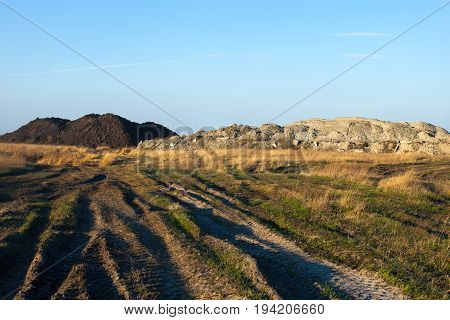 Dirt road in the field. Earth embankments in the background.