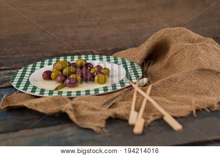 High angle view of black and green olives served in plate on wooden table