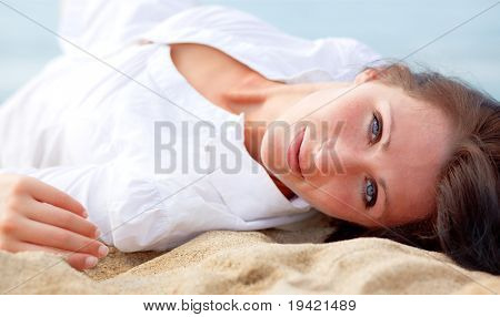 หาดสวยสนใจ sanc lying หญิงกับชายฝั่งทะเลและท้องฟ้าในพื้นหลัง