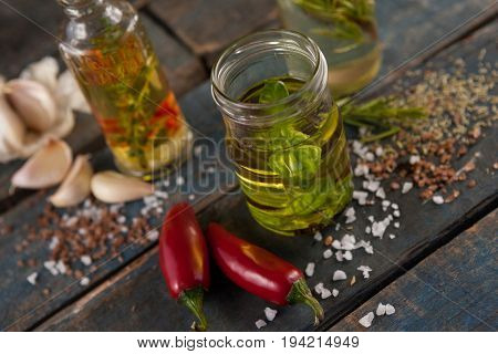 High anlge view of herbs with oil  in container amidst spices