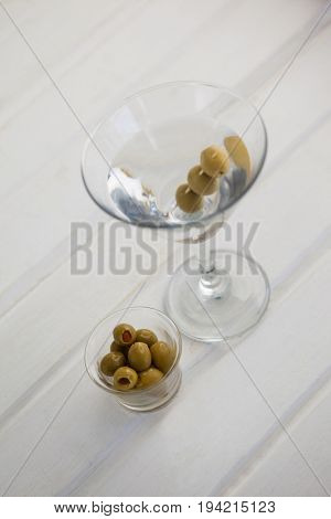 High angle view of olives in container by vodka martini on table