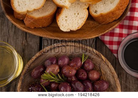 Overhead view of olives and bread with oil in container on table