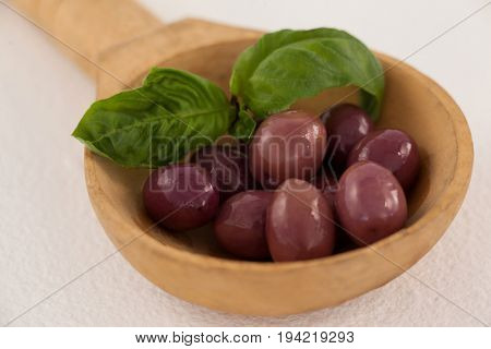 Close up of brown olives with herb in laddle on ladle