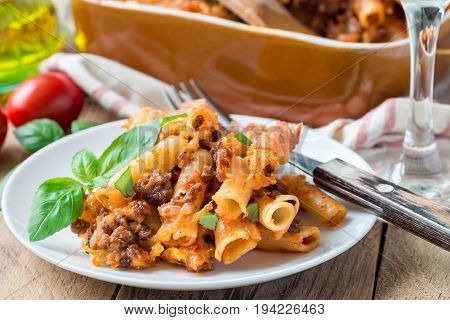 Ziti bolognese on a white plate pasta casserole with minced meat tomato sauce and cheese horizontal