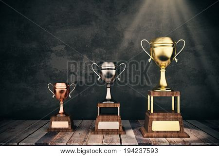 Wooden stage with golden silver and bronze winnner's cups on concrete background. Leadership concept. 3D Rendering