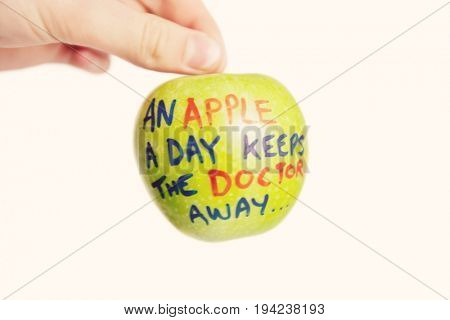 Cropped image of hand holding a granny smith apple with sayings text over white background
