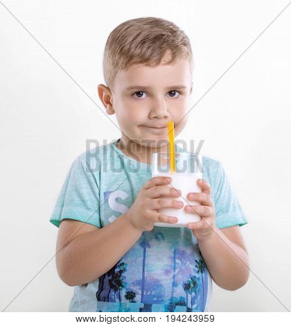 Portrait of a charming little boy who is enjoying delicious milkshake. Cheerful little kid with a glass of organic milk. Smiling boy with milk