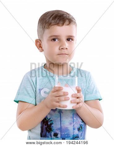 Charming little boy in a blue t-shirt is  holding a glass full of milk, isolated on a white background. Portrait of cute little boy with glass of milk.