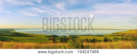 Scenic sea view from top of hills. Beautiful summer background. Amazing landscape with yellow meadows green trees blue sky steep cliffs and picturesque bay. Panoramic photo. Camping rest relax.