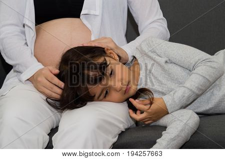 The girl is listening to belly of pregnant mother