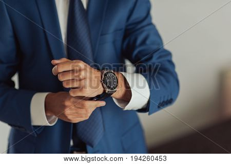 Closeup of a hand groom buttoning cuffs his hands and cufflink on his suit. Instagram colors toning