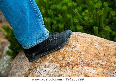 close up of feet walking step by step overcoming obstacles moving into bright future success. one person climbing over rock stones .