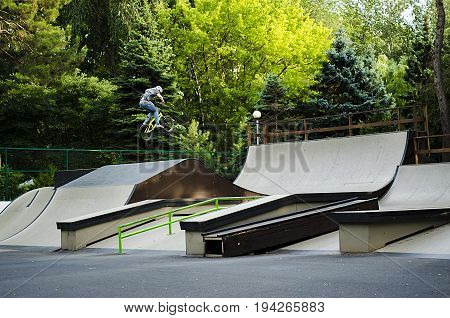 Extreme BMX rider in helmet jump in skatepark on competition. Sport bicycle concept for billboard. Brave and strong man making tricks.