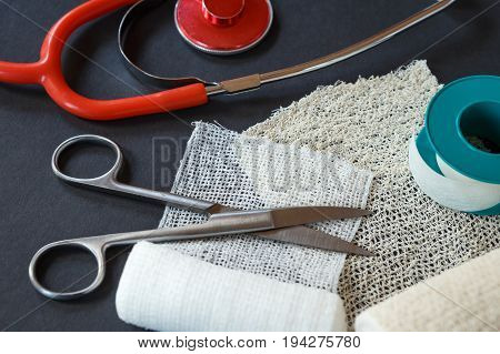 Medical Bandages With Scissors, Sticking Plaster And Medical Stethoscope On Black Background. Medica