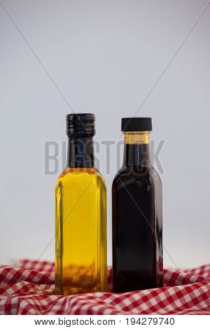 Close up of green and black olive oil in bottle on napkin against wall