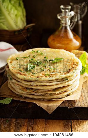 Stack of fried green onion pancakes on a wooden board