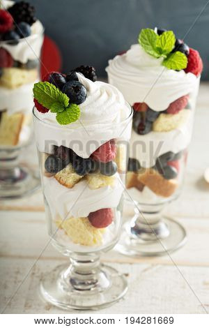 Layered dessert parfait with sweet bread, whipped cream and berries
