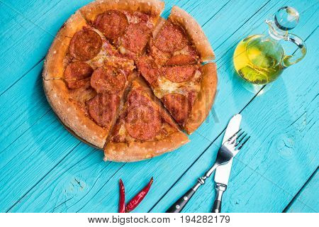 Pizza with khit and fork on blue wooden table. Italian food