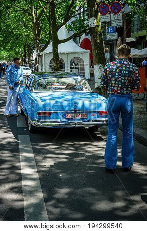 BERLIN - JUNE 17 2017: Two men dressed in the style of the 70's look at Mercedes-Benz 220 SE. Classic Days Berlin 2017.