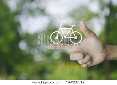 Bicycle flat icon on finger over blur green tree background Healthy lifestyle concept