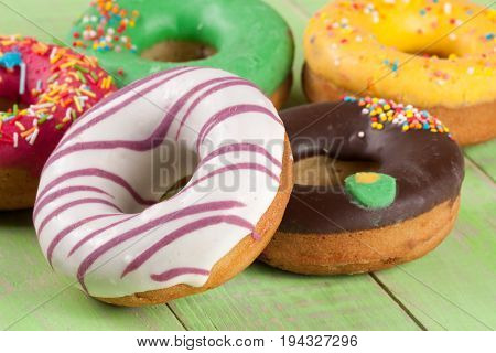 pile of glazed donuts on a green wooden background.