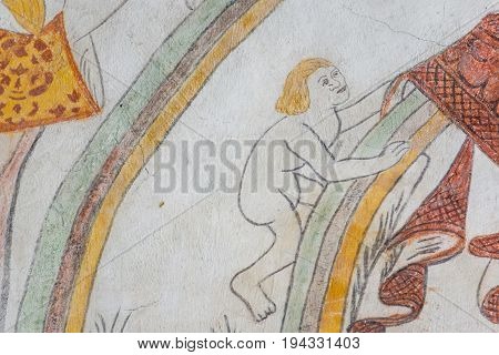 Mortal man climbing up the rainbow medieval gothic fresco in Vinderslev church Denmark June 22 2017