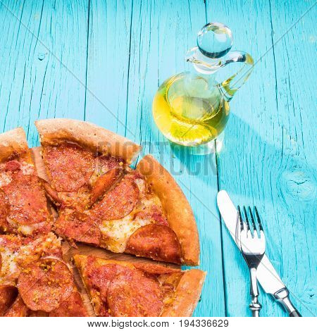 Pizza with knite and fork on blue wooden table. Italian food