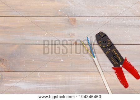 A wirestripper electrician tool lies on a wooden table. View from above