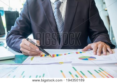 Business Man Working At Office With Laptop, Tablet And Graph Data Documents On His Desk