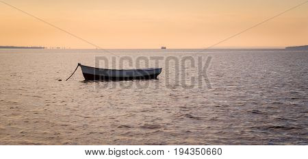 A lonely boat tied near the shore on an evening liman is very beautiful and the sun will soon set