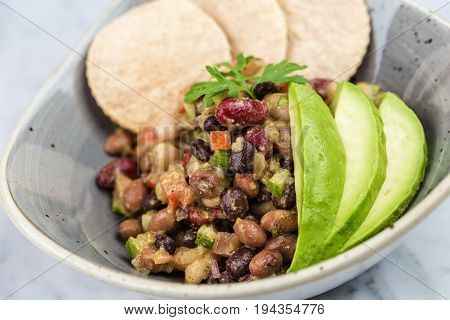 Legumes salad with crackers and avocado on marbel desk.