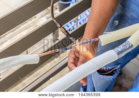 Hand of Worker welds copper tube oxyfuel gas welding repair air-condition