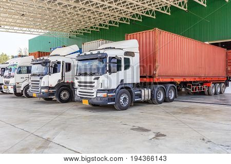 Trucks loading at cargo dock of warehouse building.