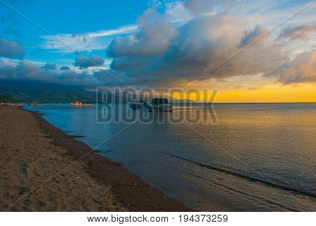 The Volcanic Sandy Beach At Sunset. The Ships At Sea. Pandan, Panay, Philippines.