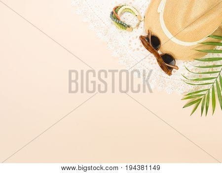 Summer fashion summer stuff on cream background. White lace dress retro sunglasses wood bracelet and straw hat. Flat lay top view