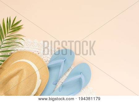 Summer fashion summer outfit on cream background. White lace dress blue flip flops and straw hat. Flat lay top view