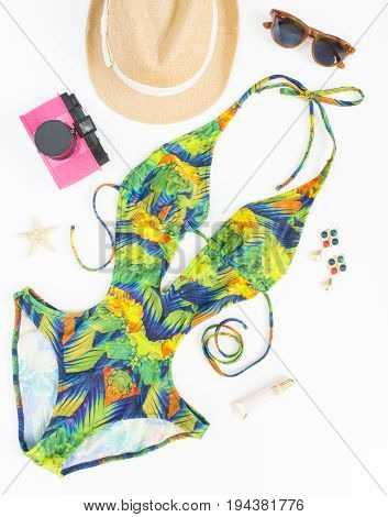 Summer outfit beach outfit summer stuff. Exotic pattern swimsuit retro sunglasses pink retro camera and straw hat. Flat lay top view.