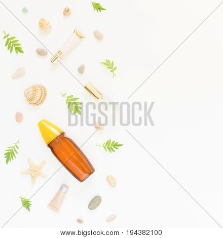 Cosmetics summer background. Cosmetics SPA makeup tubes bottles sea pebbles and shells on white background. Flat lay top view.