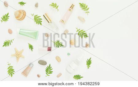 Cosmetics background. Cosmetics SPA makeup tubes, bottles, sea pebbles and shells on white background. Flat lay, top view.