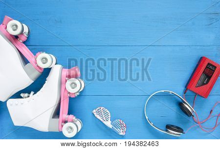 Sport, healthy lifestyle, roller skating backround. White roller skates, sunglasses, headphones and vintage tape player. Flat lay, top view.