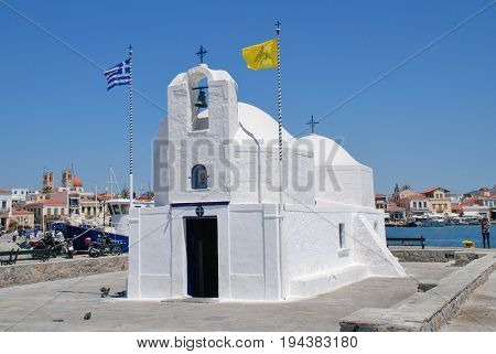 AEGINA, GREECE - APRIL 26, 2017: The whitewashed church of Agios Nikolaos on the harbour front at Aegina Town on the Greek island of Aegina. The island is a popular destination for Athenians.
