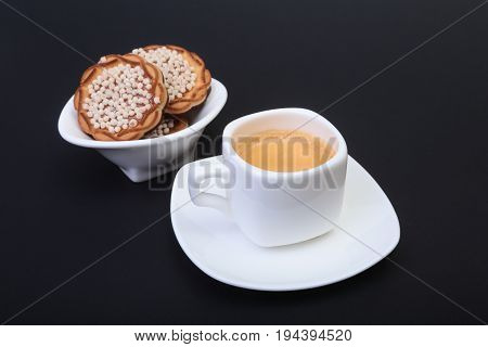 Classic espresso in white cup with homemade cake on black background. Selective focus